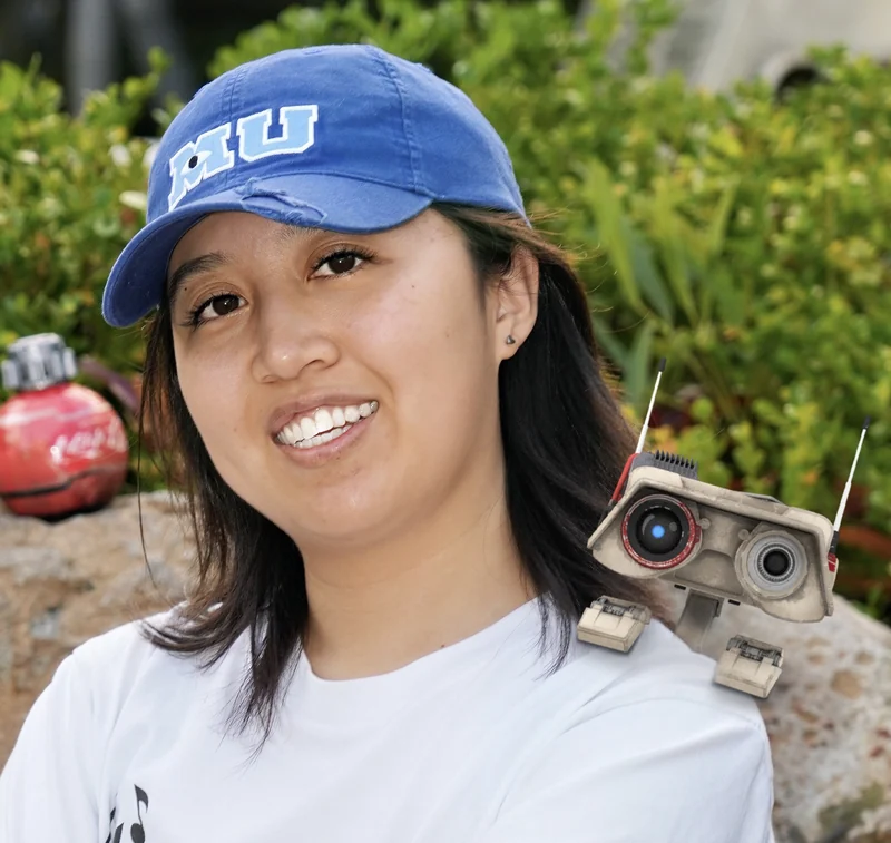 Puqi Zhou outdoors with a small robot on his shoulder.
